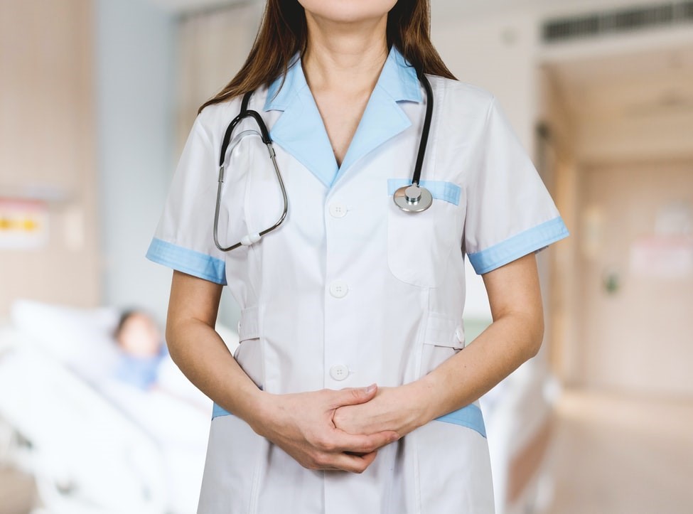 Técnico de Enfermagem de jaleco/uniforme, em um quarto de hospital com fundo desf'