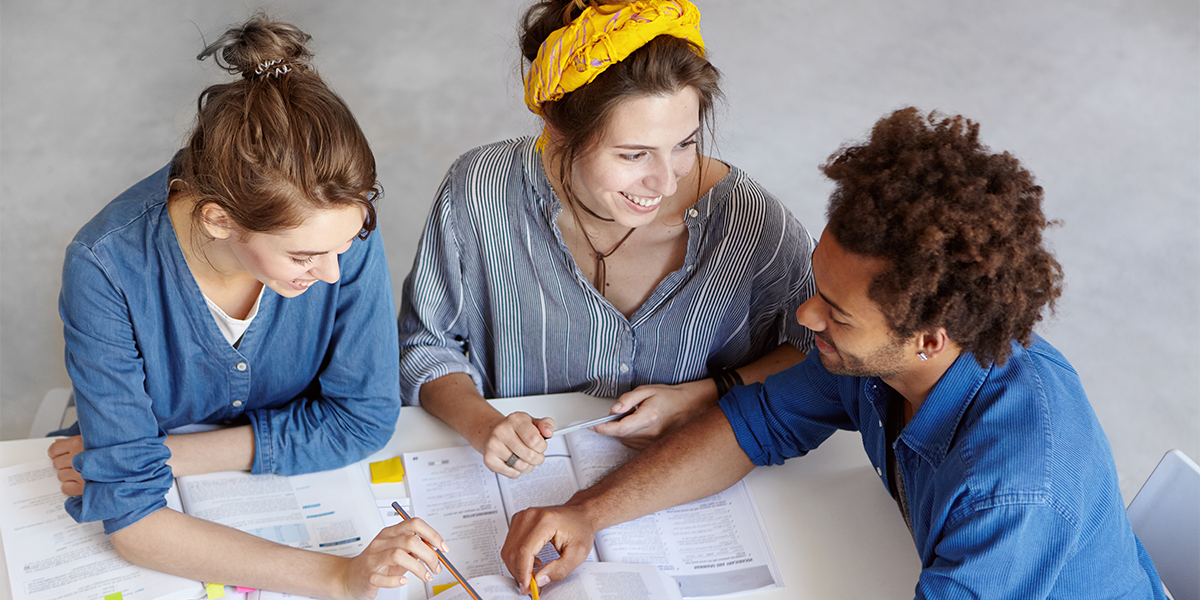 3 jovens em uma mesa de estudo para início das aulas